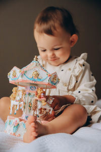 Portrait of girl playing with toy carousel on bed at home