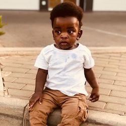 Portrait of cute boy sitting on footpath
