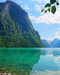 Scenic view of sea by mountains against sky