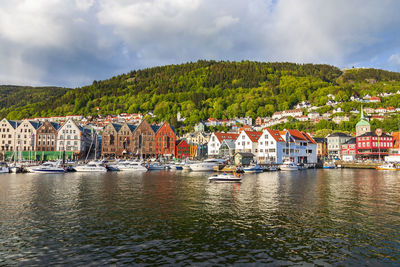 Sailboats in town by buildings in city against sky