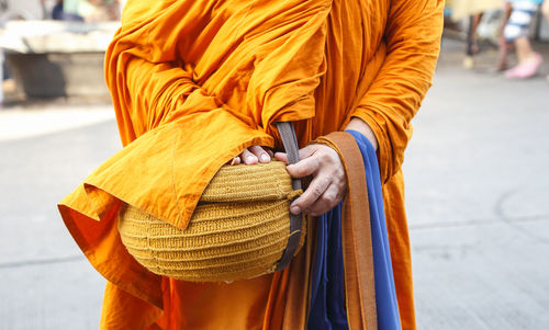 Midsection of monk with container standing in temple