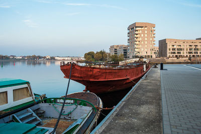 Boats moored at harbor against buildings in city