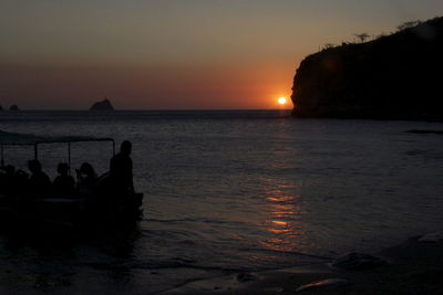 Silhouette of people in sea at sunset