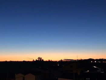 Silhouette buildings against blue sky at sunset