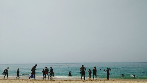 People on beach against clear sky