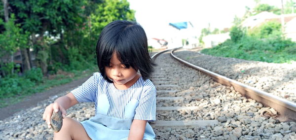 Cute girl sitting on railroad track