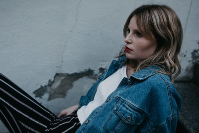 Thoughtful woman wearing denim jacket while sitting outdoors