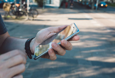 Midsection of man using mobile phone on street