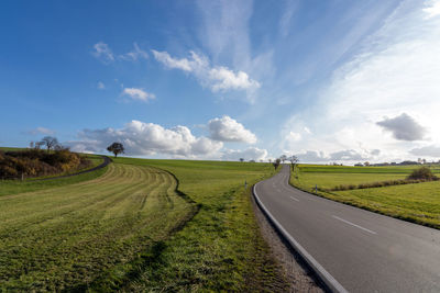 Road amidst field against sky