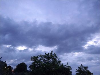 Low angle view of silhouette trees against storm clouds