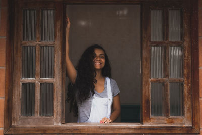 Portrait of smiling young woman standing against wall