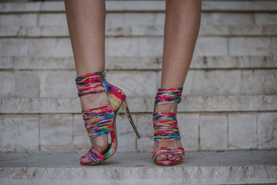 Low section of woman wearing multi colored stiletto standing on staircase
