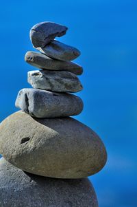 Stack of stones on rock against blue sky