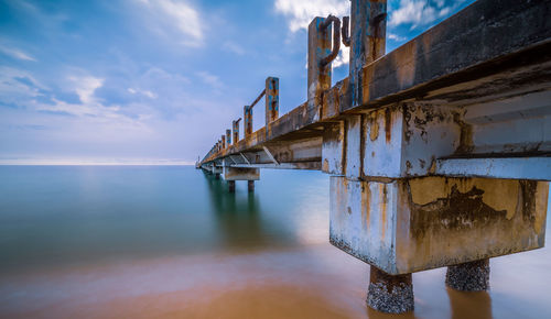 View of metal structure by sea against sky