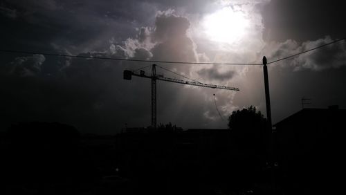 Low angle view of silhouette electricity pylon against dramatic sky