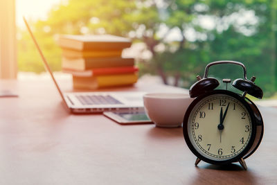 Close-up of alarm clock on table against window