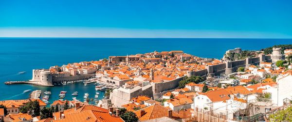 High angle view of buildings by sea against blue sky