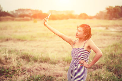 Woman taking selfie with smart phone on field