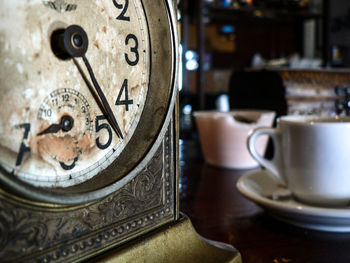 Close-up of old-fashioned clock and coffee cup on table