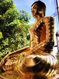 Statue of man sitting by tree