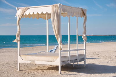 Chair on beach against sky