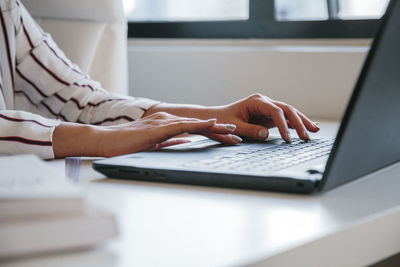 Midsection of woman using laptop on table