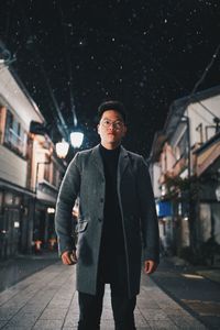 Portrait of young man standing on street at night