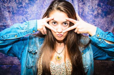 Portrait of playful young woman making face against wall