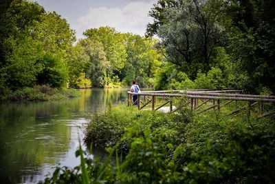 Woman cycling on river amidst trees