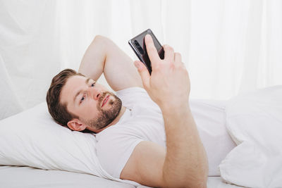 Young woman using mobile phone on bed at home