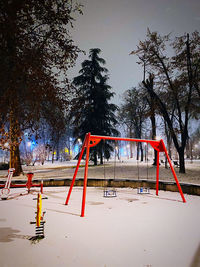 Empty swing in park against sky during winter