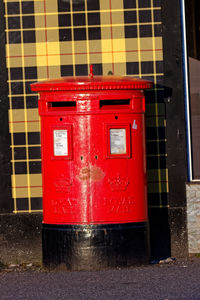 Red mailbox on road by building in city