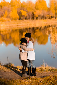 Full length of woman standing by lake during autumn