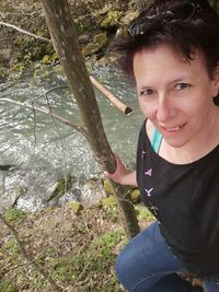 Portrait of smiling girl sitting by tree