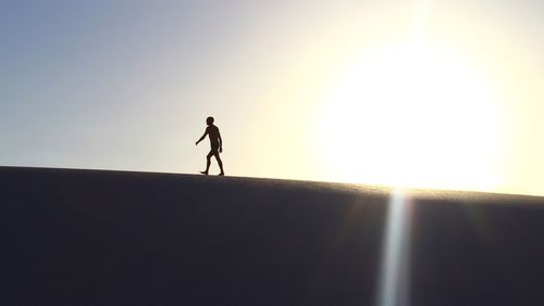 Silhouette man walking against sky during sunset