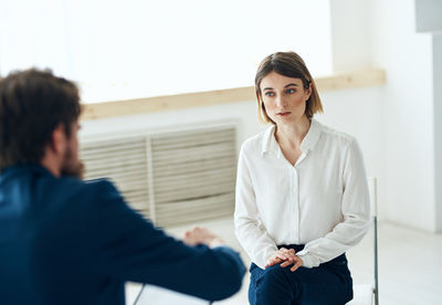 Portrait of young woman standing against wall