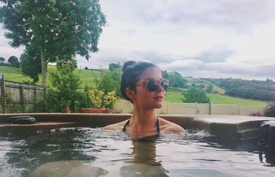 Young woman in swimming pool against river