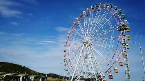 Low angle view of ferris wheel against blue sky