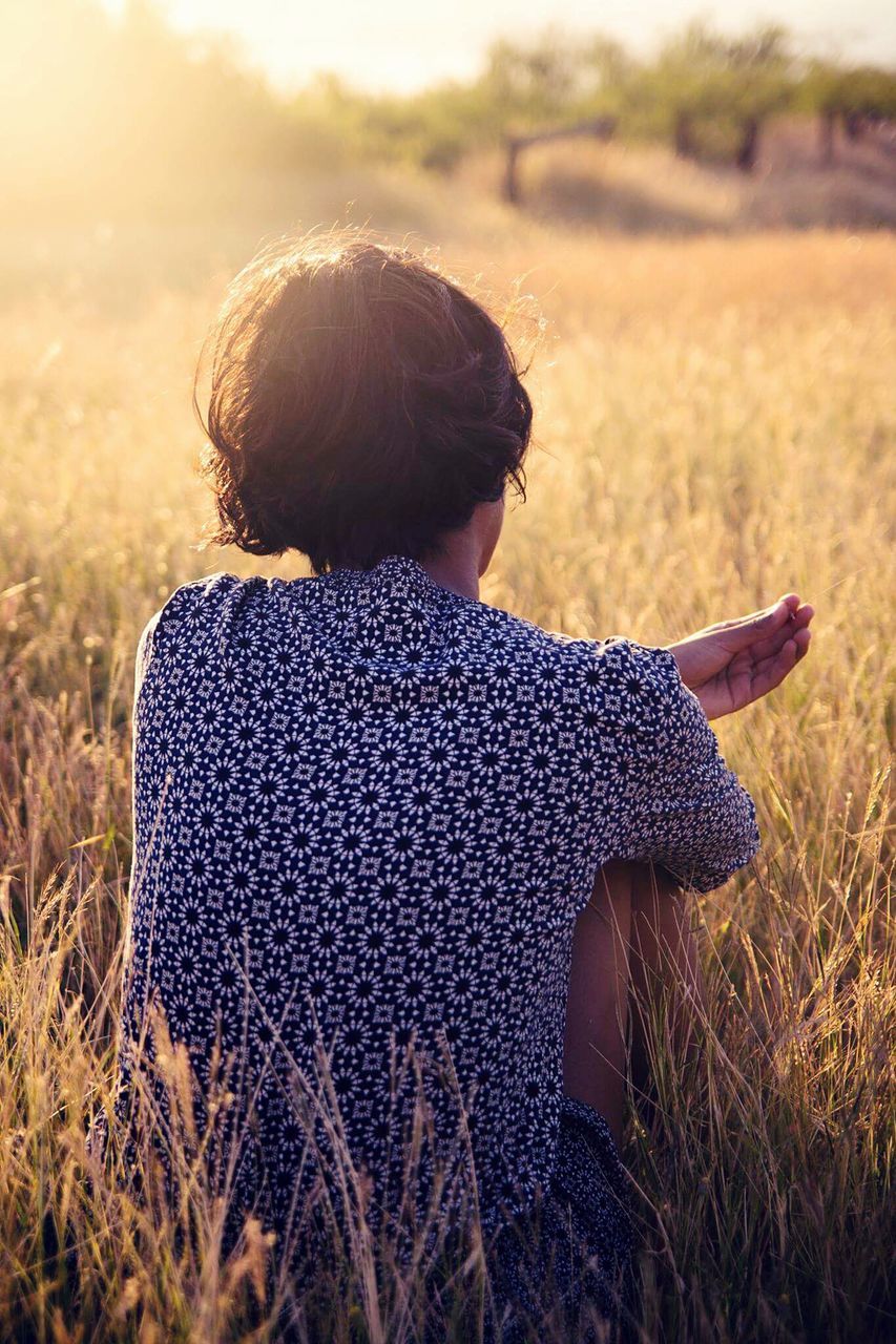 REAR VIEW OF YOUNG WOMAN STANDING ON FIELD