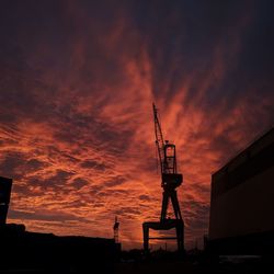 Silhouette cranes against orange sky