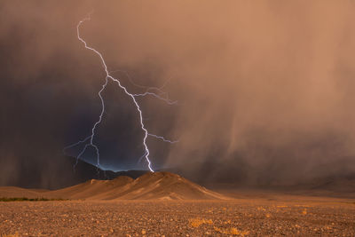 View of lightning over mountains during storm during sunset