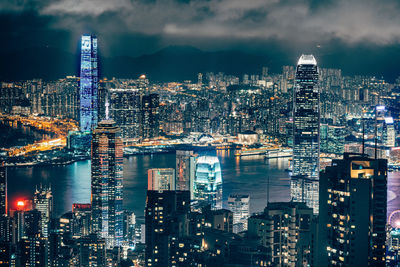 Illuminated modern buildings in city against sky at night