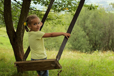 Portrait of boy sitting on swing at park