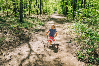 Cute girl walking on dirt road in forest