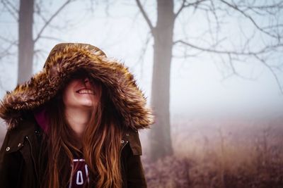 Smiling young woman in warm clothing during foggy weather