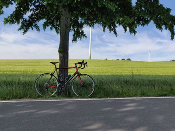 Bicycle on road amidst field against sky