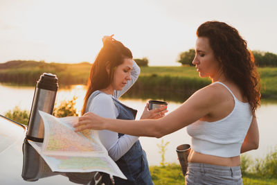 Young woman using smart phone against sky