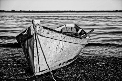 Abandoned boat moored on beach against sky