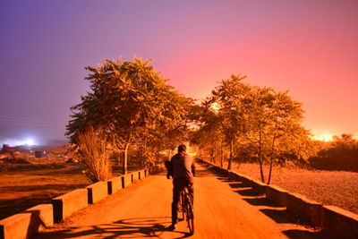 Man riding bicycle on road at night