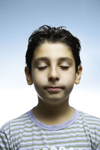 Close-up of boy meditating against clear sky